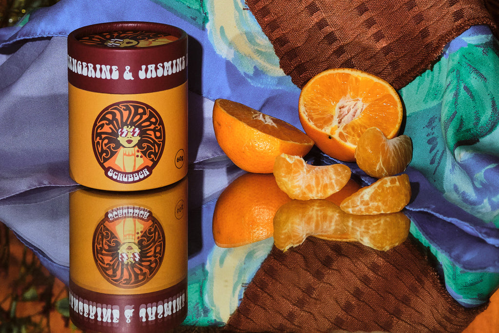 Cardboard eco friendly tube product with oranges on a colorful fabric background. dry shampoo