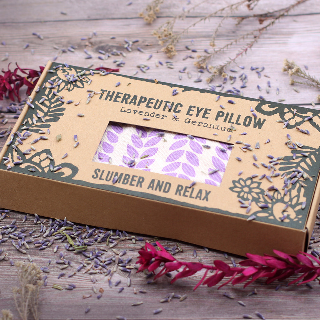Therapeutic eye pillow packaging with lavender and geranium on a wooden surface.  Slumber and relax