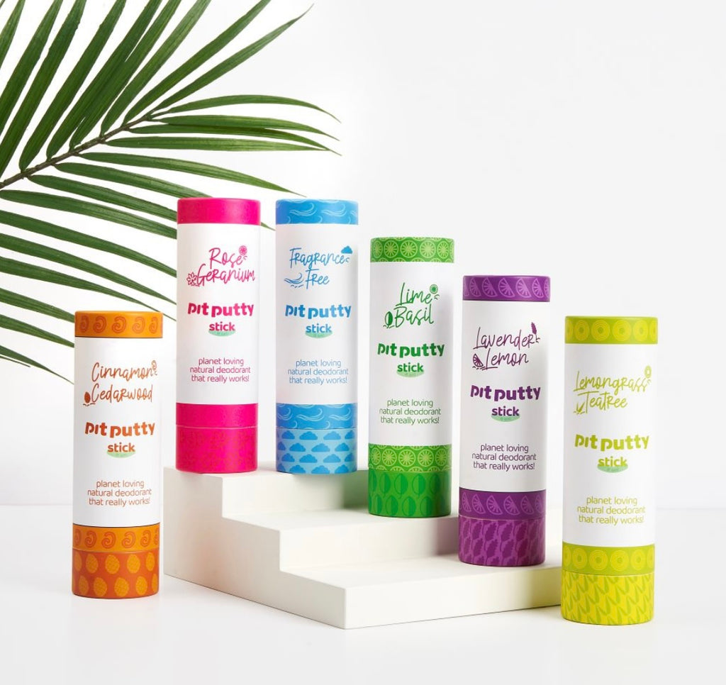 Collection of pit putty sticks with colorful lids on a white surface with a leafy green background. natural deodorants. mini sticks. natural collection